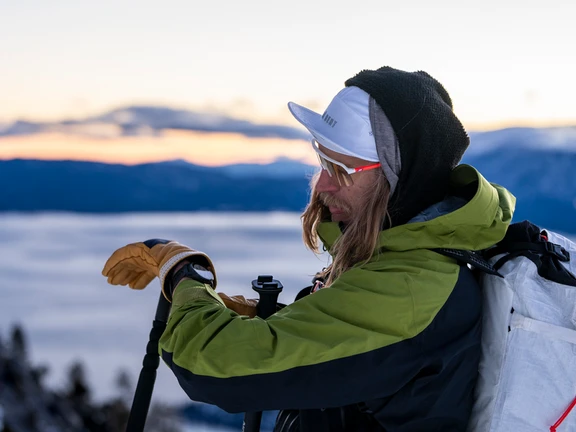 Cody Townsend consulta su reloj en la montaña con bastones de esquí.