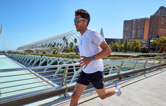 Läufer in weißem Shirt joggt vor moderner Architektur in Valencia.