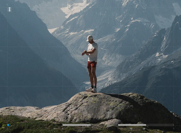 a man standing on a cliff looking at his watch