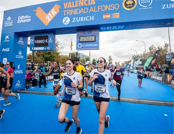 Runners crossing the finish line at the Valencia Half Marathon under a COROS-branded timer.