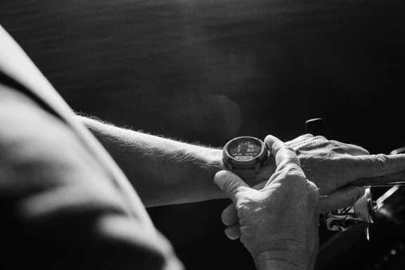 Person checking COROS NOMAD watch displaying fishing metrics while on a boat.
