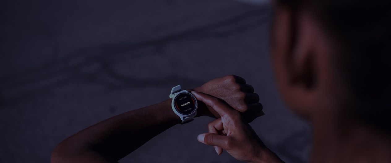A close-up image of a running operating a COROS PACE 2 White Watch in Night Mode at night.