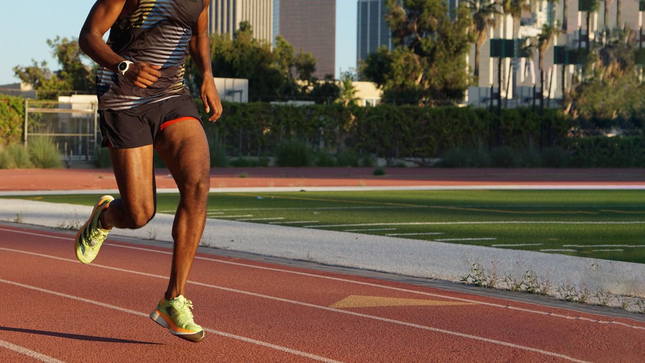 A close-up image of a male runner training on a track with a COROS PACE 2 White watch.