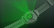 Gambar sensor detak jantung optik yang memancarkan lampu hijau dari jam tangan COROS PACE 3 hitam dengan tali silikon hitam.
