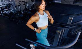 A female runner running on a treadmill wearing a COROS PACE 3 watch.